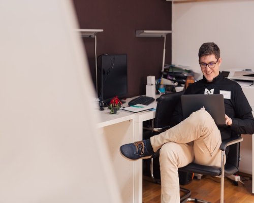Two modern professional initiative creators collaborating next to an office laptop inside a well lit modern room in Cluj-Napoca